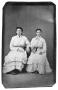 Photograph: [Two seated women in tiered dresses]