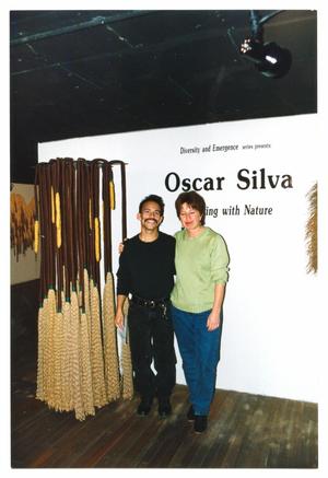 Primary view of object titled '[Oscar Silva and Unnamed Woman in Front of Title Wall]'.