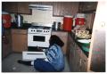 Photograph: [Woman Seated on Floor in Kitchen]