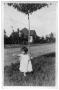 Primary view of Child standing in the grass next to a street