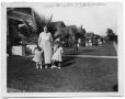 Photograph: Mrs. Kruder and two children in the backyard of a house