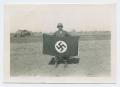 Photograph: [Donald Coombes Holding a Nazi Flag]