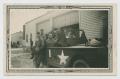 Photograph: [Six Soldiers Posing with Scout Car by Garage]