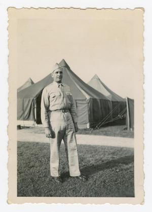 Primary view of object titled '[Dan Melli Standing in Front of Tents]'.