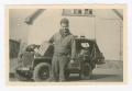 Photograph: [George Benack Standing in Front of a Jeep]