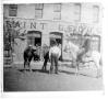 Photograph: [Two men with two horses in front of the Saint George building]