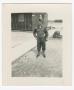 Photograph: [Soldier Standing by a Building and Sidewalk]