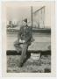 Photograph: [A Soldier Sitting on a Bridge Railing]