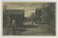 Postcard: [Postcard of Two Wooden Houses and a Woman]