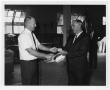 Photograph: [Men Shaking Hands and Exchanging Piece of Paper]
