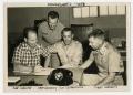 Photograph: [Smith, Downey, Rutherford, and Grimes at Desk]
