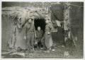 Photograph: [Three Soldiers Standing Outside of Their Hut]