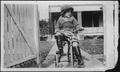 Photograph: [Photograph of Mary Jones riding her tricycle on a sidewalk]
