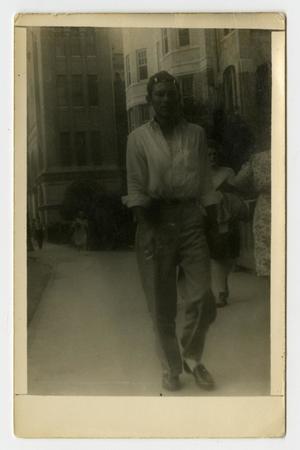 Primary view of object titled '[Photograph of a Man Walking Down a Sidewalk]'.