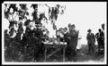 Photograph: [Group of men standing around a table drinking bottled beverages at C…
