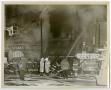 Photograph: [Row of Firefighters in Front of Smoking Building]