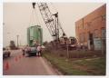 Photograph: [Crane placing old power plant equipment on truck]