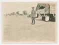 Photograph: [Harry Bickler Stands, Guarding a Truck]
