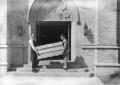 Photograph: [Two Men Carry a Crate into Shelton Chapel]