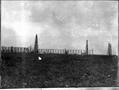 Primary view of [Photograph of four large oil derricks in a field]