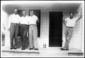 Photograph: [Photograph of four young men standing on the front porch of a house]