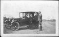 Photograph: [Woman sitting in an automobile with three people standing nearby]