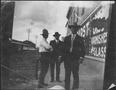 Photograph: [Three men standing on a street sidewalk]