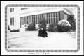 Photograph: [Two women sitting in the snow covered lawn of the George Ranch house]