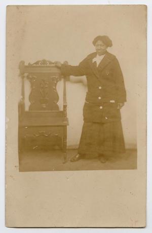 Primary view of object titled '[Postcard of an African-American Woman Standing Next to a Chair]'.